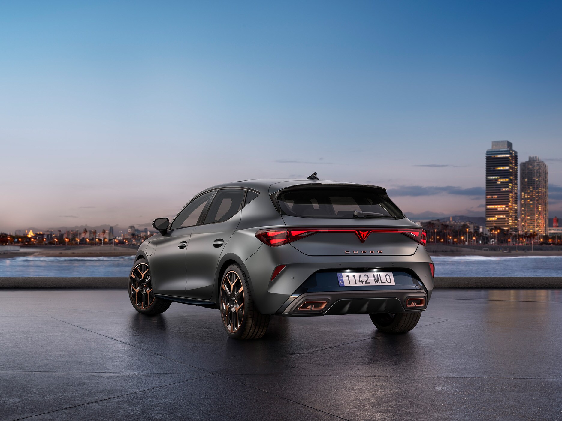 The new CUPRA Leon parked in an urban area, facing the city buildings at sunset.