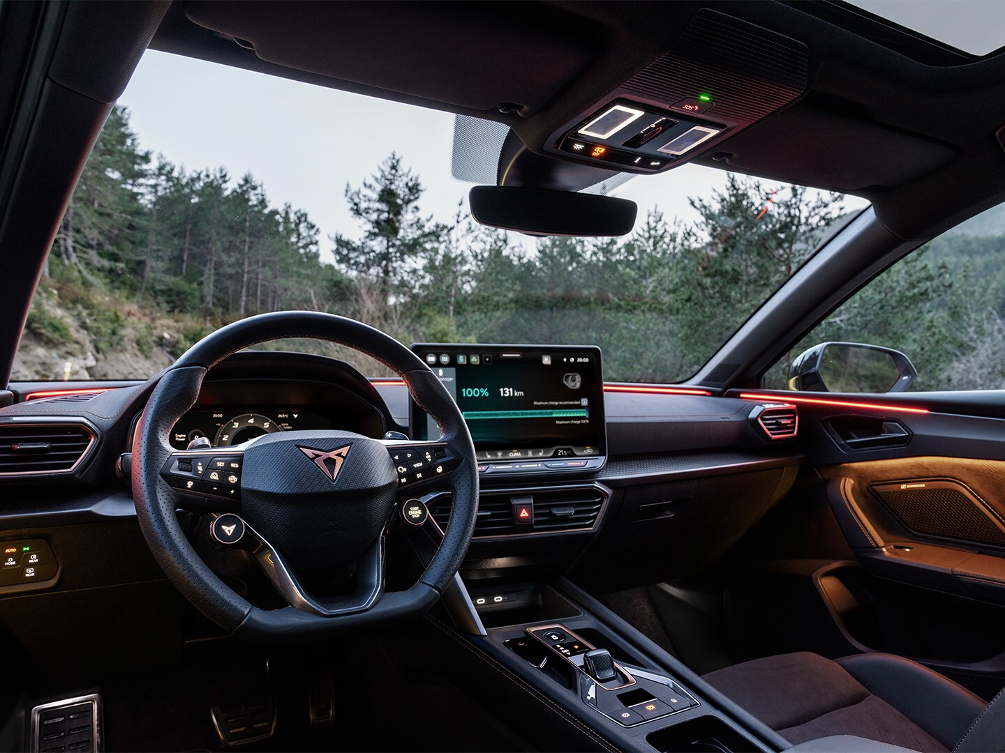 Interior view of the CUPRA Leon, featuring a driver-oriented cockpit, parked outdoors in a wooded setting.